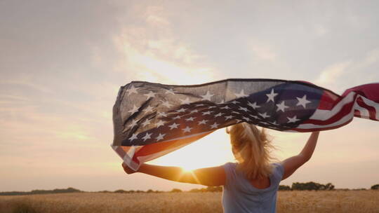 举着美国国旗的女人在田野里奔跑