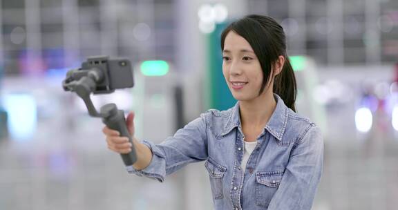 在机场用手机拍摄视频的女子