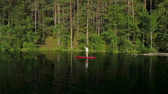 一名女子在森林中的红色滑板上航行