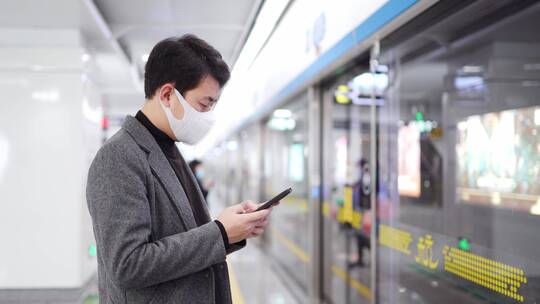 年轻人戴着口罩在地铁站使用手机