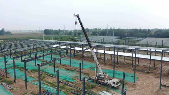 大型吊车在建设中的钢结构厂房中作业航拍视频素材模板下载