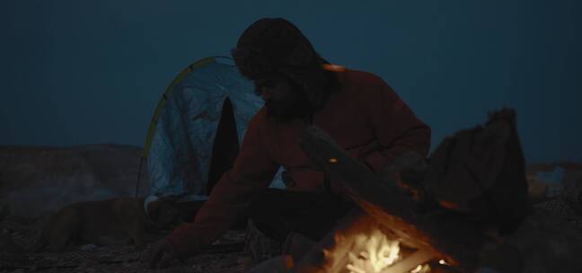 男人户外露营坐在火堆前烤火