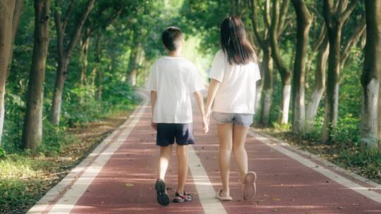 男孩女孩牵手在林荫小道上散步4k视频素材视频素材模板下载