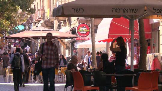 行人挤满了以色列耶路撒冷新城的咖啡馆和现代街道