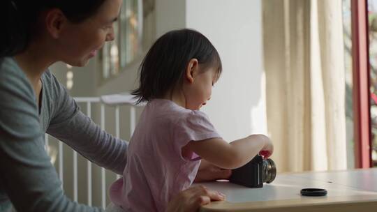 小宝宝在妈妈指导下摆弄相机学习摄影