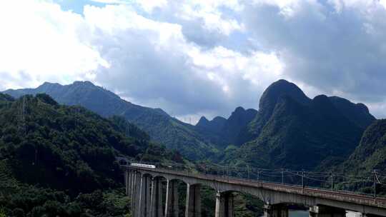 高铁动车列车高铁经过蓝天白云下的山谷乡村