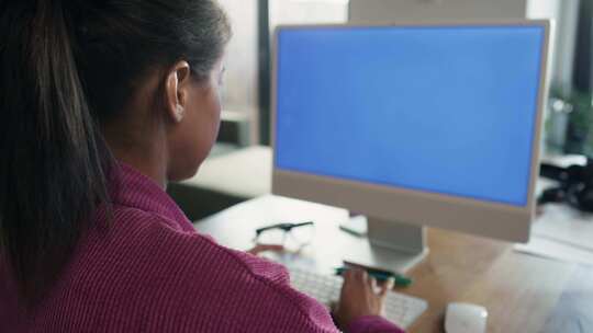 蓝屏上在电脑上工作的混血女人的后视图。用红色氦气相机在8K拍摄。