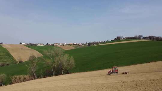 农业公司红色拖拉机下坡耕作和准备农业有机土壤的空中