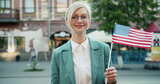 漂亮金发女郎站在户外，美国国旗微笑的肖像高清在线视频素材下载