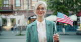 漂亮金发女郎站在户外，美国国旗微笑的肖像高清在线视频素材下载