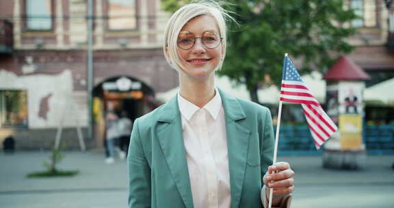 漂亮金发女郎站在户外，美国国旗微笑的肖像