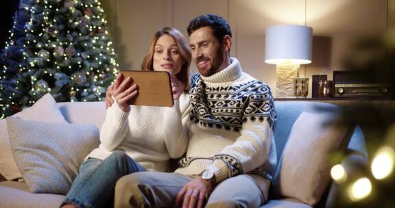 圣诞节夫妻使用平板和家人视频