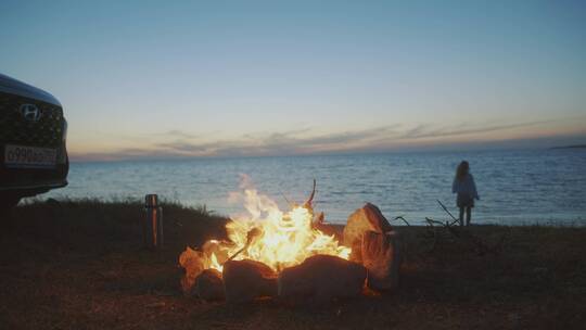 女人在篝火旁的海边散步视频素材模板下载