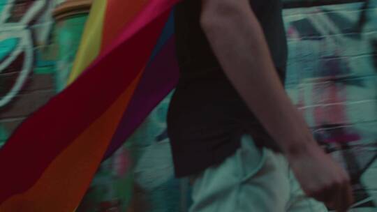 一个拿着彩虹旗的人走在街上