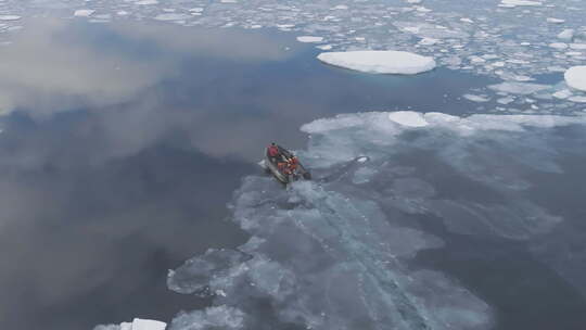 远征船上的人的鸟瞰图在汹涌的冰水中航行。