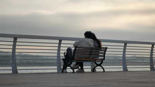 一对情侣坐在海边公园的椅子上谈情说爱