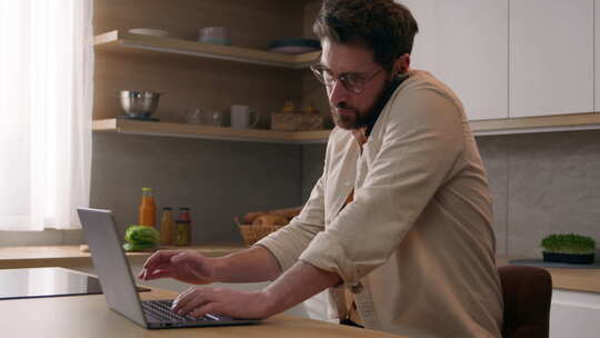 现代厨房里带笔记本电脑的男性自由职业者商