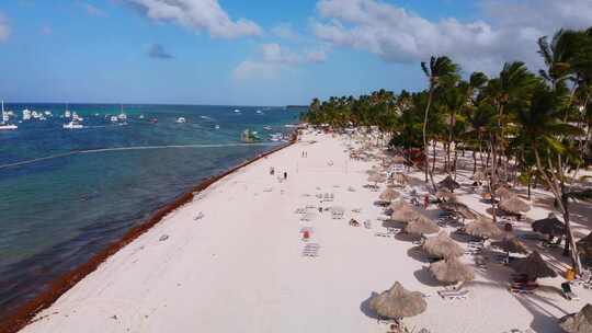 满是日光浴床的沙滩，加勒比海上的船只，多米尼加共和国蓬塔卡纳的巴瓦罗度假村，