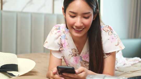 亚洲美女计划通过手机和信用卡在家里的床上愉快地旅行。