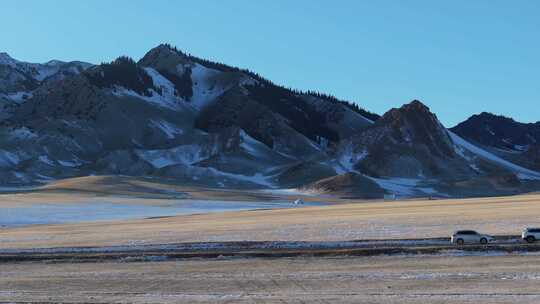 航拍冬季新疆赛里木湖雪山环湖公路夕阳车辆