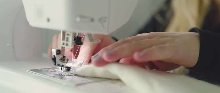 女人用她的缝纫机修剪毛茸茸的白色材料