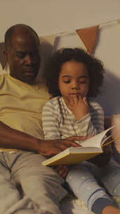 父亲睡前给无聊的孩子读童话的垂直视频素材模板下载