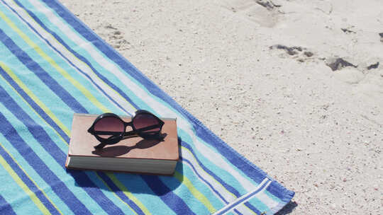 躺在海滩上的太阳镜、书籍、毛巾和海滩设备的视频视频素材模板下载