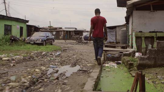 男人走在贫民窟的土路上