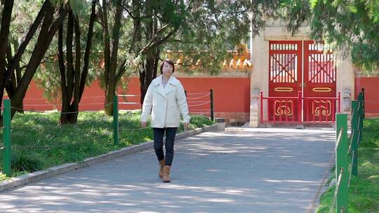 秋天走在北京地坛公园红墙外的中国女性