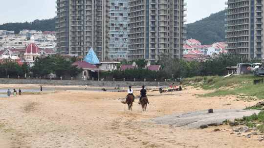 长焦航拍威海金海路沙滩上的骑马人