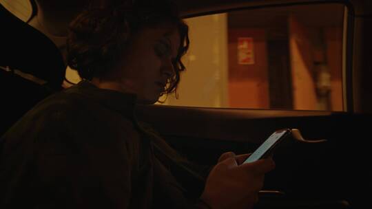 女乘客坐在汽车里玩手机