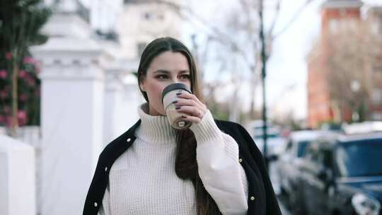 拿着杯子走在人行道上的女人