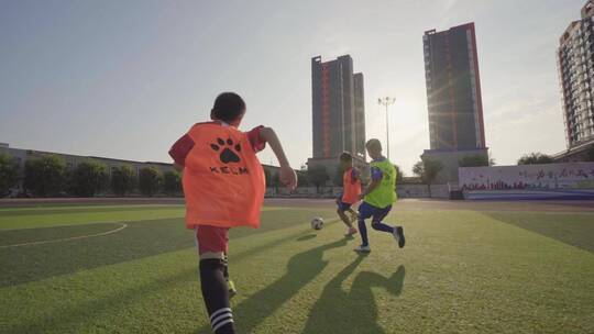 夕阳下小学生在球场踢足球视频素材模板下载