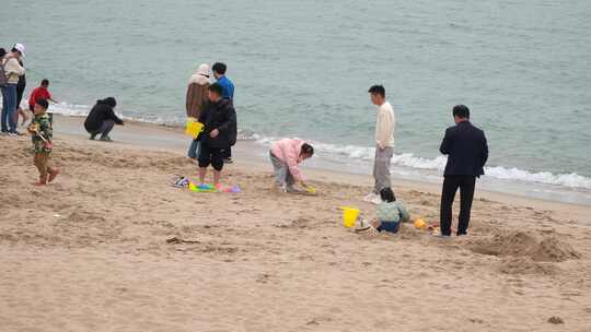 一群旅客在海边沙滩赶海玩耍