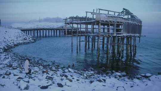 一个走在白雪覆盖的岩石海岸上的女人