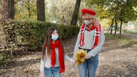 戴口罩的女人和女孩在公园散步