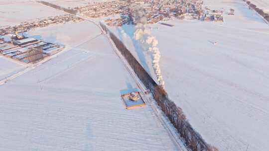 航拍中国东北冬季雪景中的蒸汽火车穿过村庄