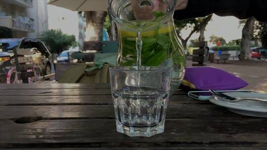 街头的木桌上向玻璃杯里倒柠檬水