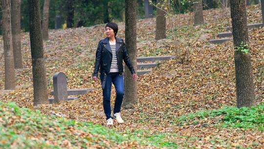 4K实拍走在秋天落满树叶树林里的东方女性视频素材模板下载