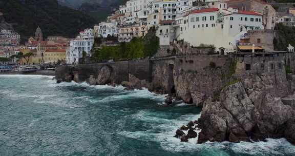 海岸悬崖上的海滨酒店，海浪拍打着。白天意大利南部的阿马尔菲海岸。aer