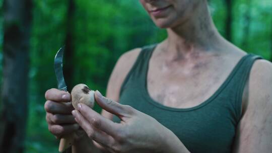 女孩在森林里用刀切割蘑菇