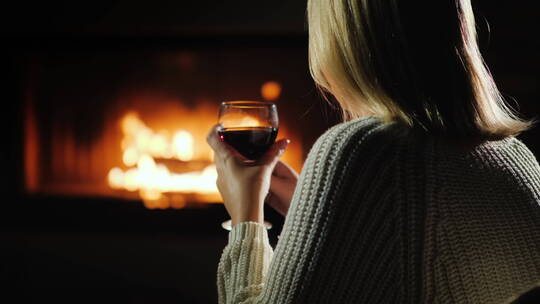 坐在壁炉旁喝红酒的女人
