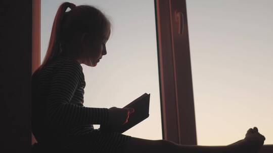 一个小女孩在窗台上读书