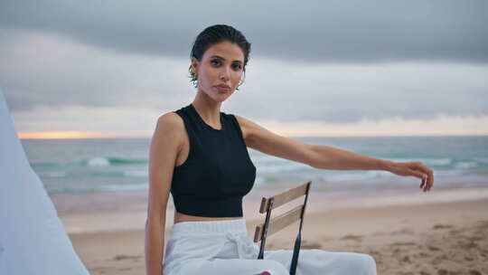 时尚模特在阴天拍摄海岸性感美女坐椅
