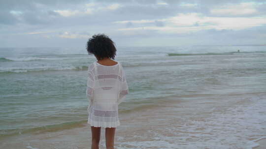 穿着白色服装思考海洋海滩的女人