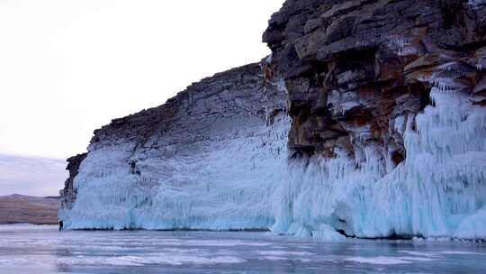 游客们在结冰的湖面上拍摄冰雪覆盖的落基山