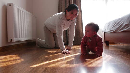 妈妈和宝宝在家里一起玩耍在地板上爬行