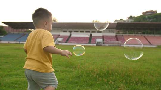 小男孩在足球场追泡泡，童年时光
