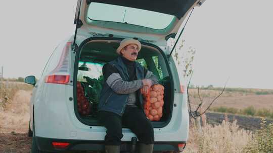 收获遐想一个年长的农民在汽车后备箱的土豆