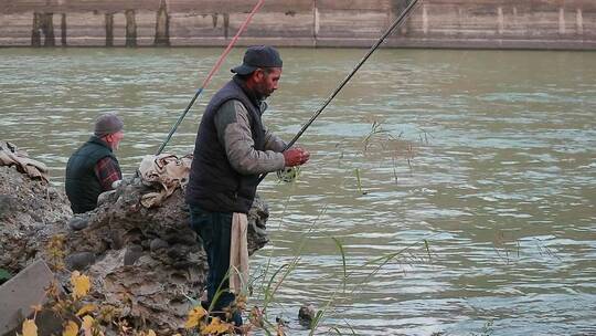两个人在河边用鱼竿钓鱼